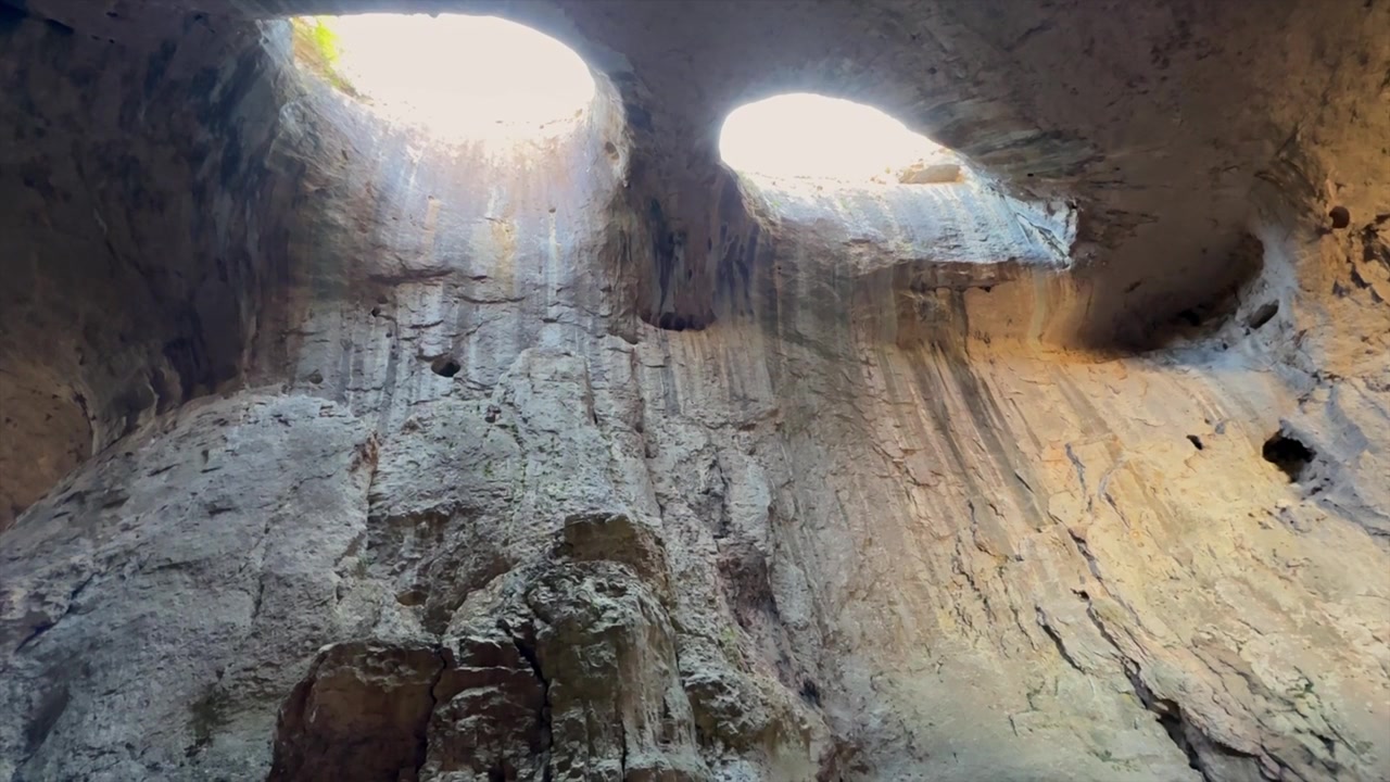 Natural landmark Prohodna cave in Bulgaria, featuring two eye shaped holes in the ceiling known as the Eyes of God illuminating the cavern