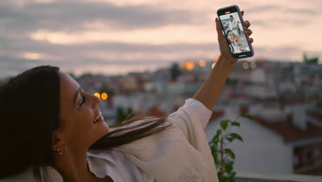 mujer positiva tomando una selfie en un primer plano en el balcón al atardecer. personas tomando fotos