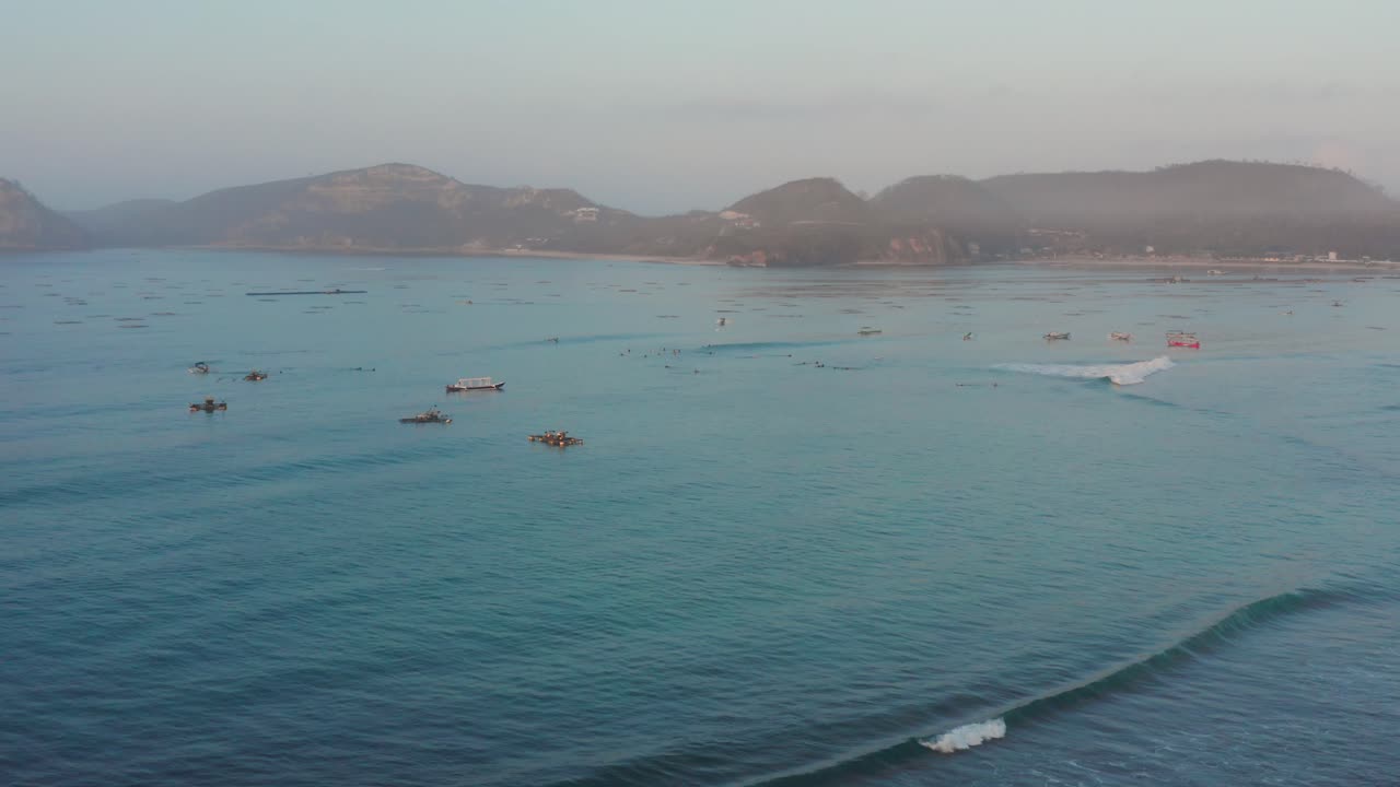 롬복에 있는 게루푹의 서핑 장소에서 일출, 어선과 서퍼가 있는 만의 전망