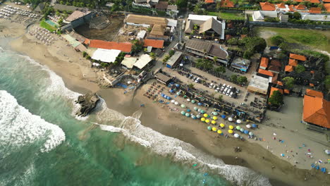 Aerial-panorama-of-sunbeds-and-umbrellas-on-popular-Batu-Bolong-beach,-Bali,-Indonesia