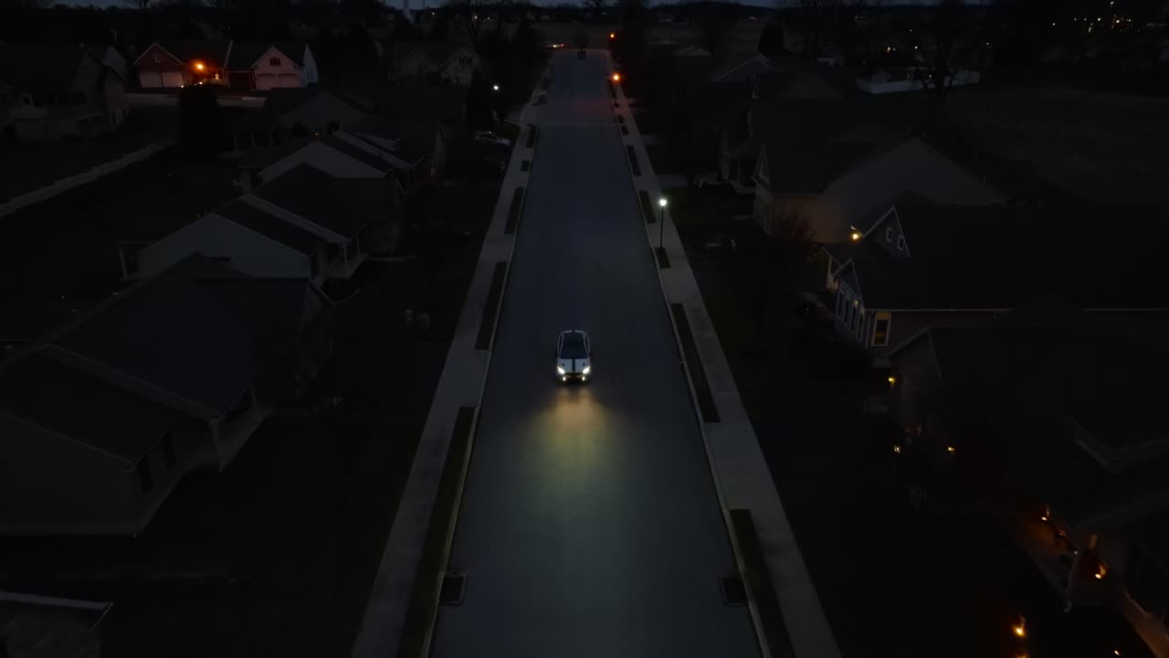 밤에 어두운 미국 동네를 가로질러 운전하는 자동차의 조감도