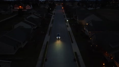 aerial view of car driving through dark american neighborhood at night