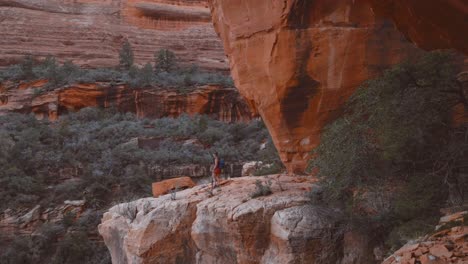 Caucasian-female-brunette-hiker-walks-out-onto-extreme-ledge-in-Boynton-Canyon