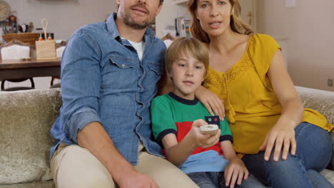 parents watching tv with their son on couch