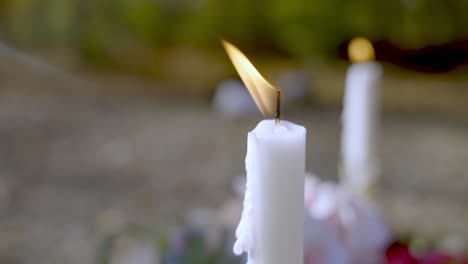 white candle burning on top of new grave, close up slow motion view