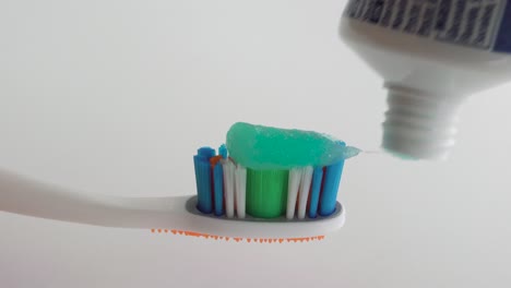 toothpaste being applied on a toothbrush. close up