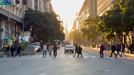 pedestrians and traffic on a busy city street at golden hour