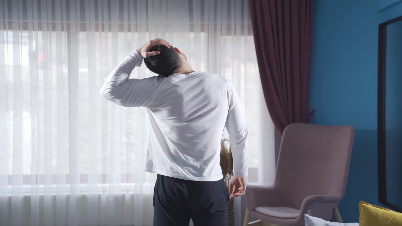 목과 머리를  ⁇ 어서 집에서 운동을 하는 젊은 운동선수.