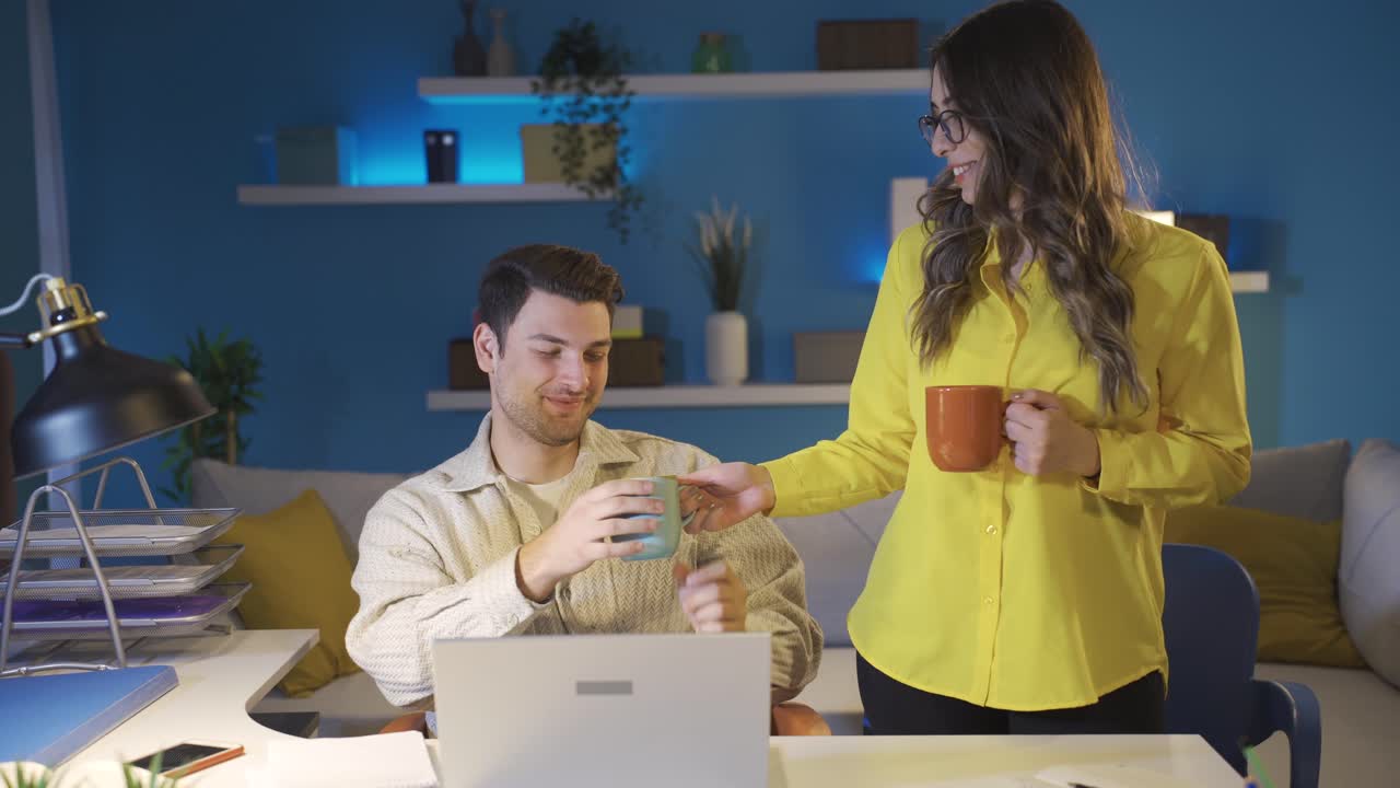 una mujer le trae café a su cansado y somnoliento marido.