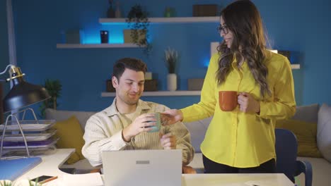 Woman-brings-coffee-to-her-tired-and-sleepy-husband.-Freelance-husband-and-wife.