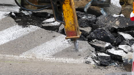 hydraulic breaker breaking up asphalt, roadwork, close up static