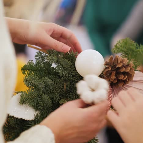 woman with child fixes jewelry on christmas wreath