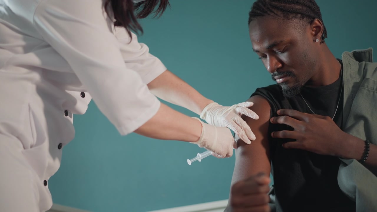 Clinician confidently provides vaccination to attentive patient in clinic setting. Medical practitioner carefully delivers vaccine to patient with focused attention and gentle interaction