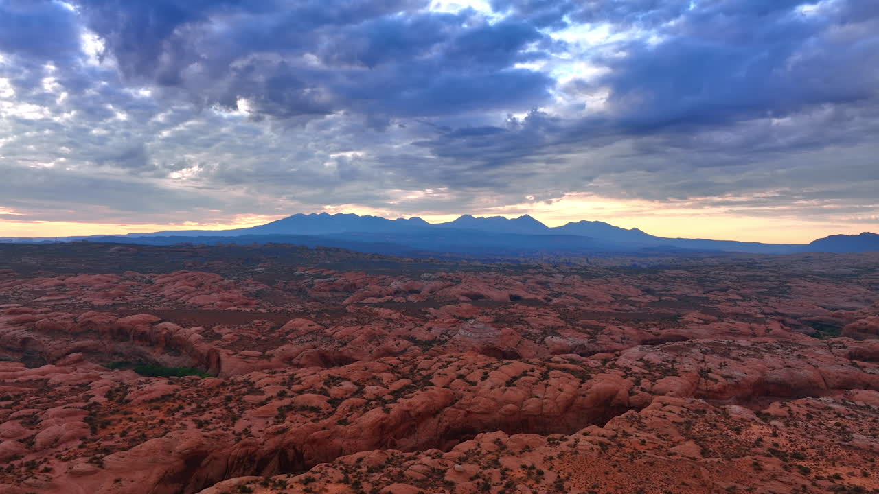 Grey cloudscape accumulated in the sky over the dry rocky landscape. Sunset time in the Arches National Park, Utah, USA from drone