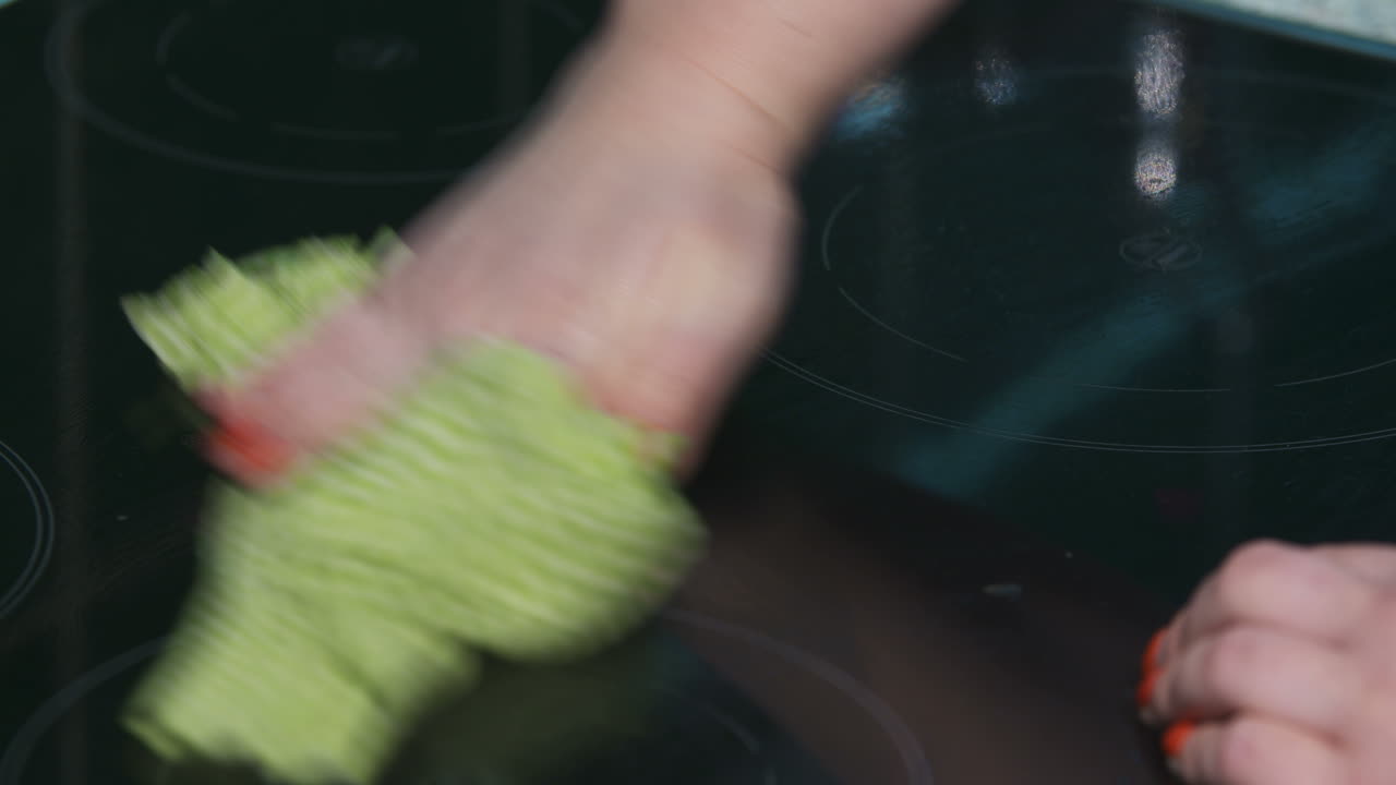 Woman Cleans The Electric Stove With A Cloth