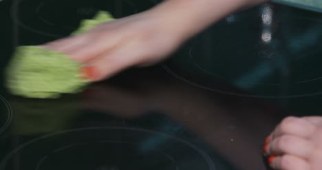 woman cleans the electric stove with a cloth