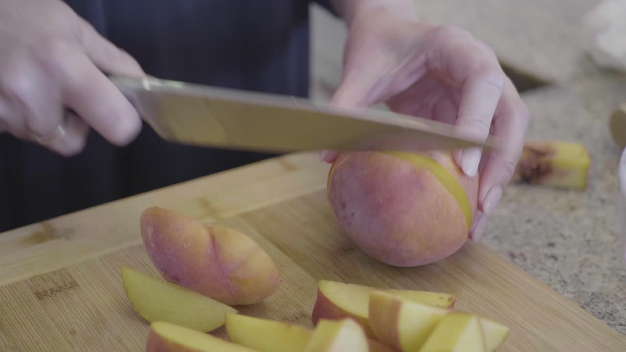 una chef mujer está cortando melocotones en una tabla de madera en la cocina