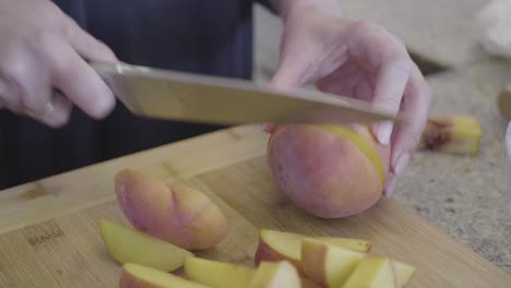 una chef mujer está cortando melocotones en una tabla de madera en la cocina