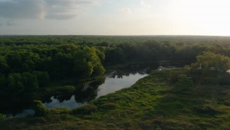 Aerial-drone-pan-over-serene-waterway-with-two-kayaking-fisherman-at-sunrise