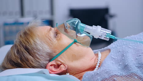 portrait of retired woman breathing with difficulties in oxygen mask