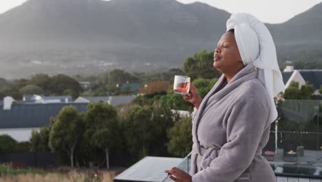 african american plus size woman drinking tea on balcony, unaltered, copy space, slow motion