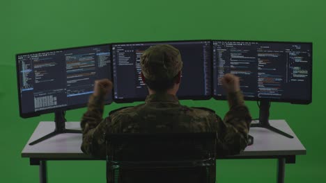 back view of happy asian man soldier developer celebrating while write code with multiple computer screens in green screen studio