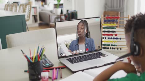 zweirassiger junge auf laptop lernt online mit afroamerikanischem schulmädchen