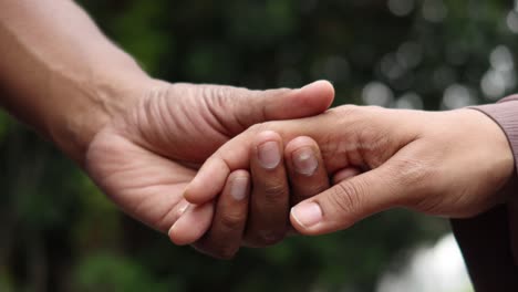 primer plano de una pareja cogida de las manos contra un fondo naranja