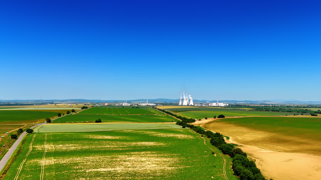 Drone footage over the countryside fields on sunny day. Large industrial plant territory at backdrop. Slovakia industry