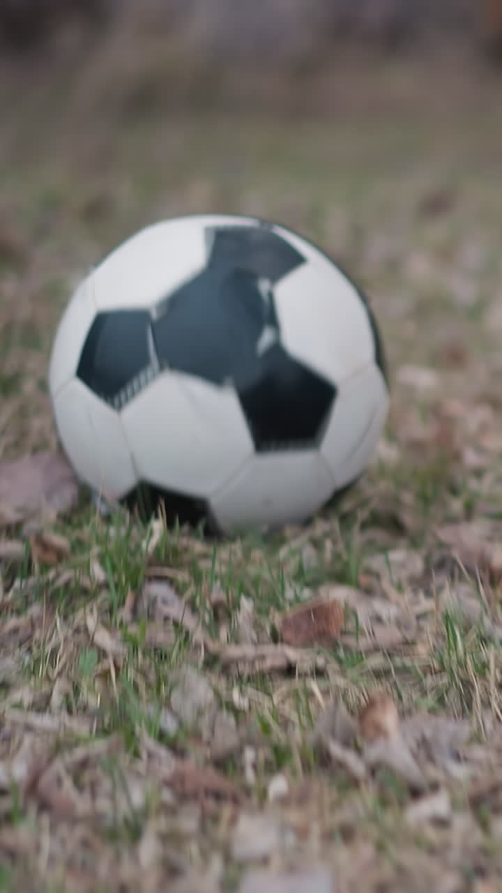 Close-up leg view of someone running with a soccer ball on a grassy field, captured just before they shoot the ball away