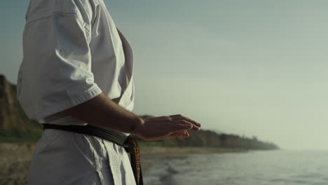 maestro de karate perfeccionando ejercicios de lucha en la orilla del mar de cerca. entrenamiento de hombre.