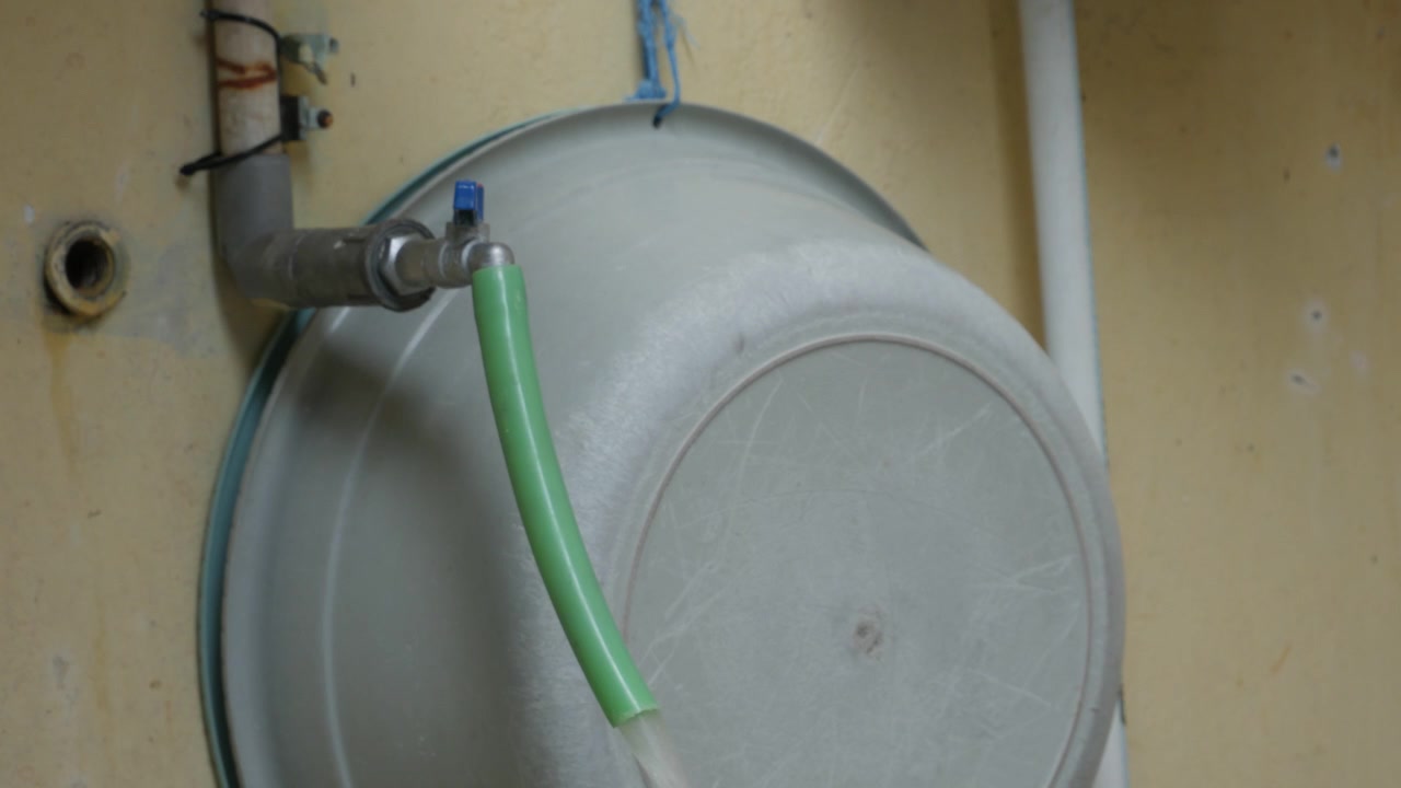 Mano che apre un rubinetto dell'acqua collegato a un'utenza domestica all'aperto