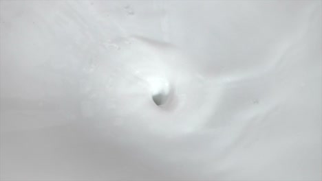 footage of creamy milk swirling whirlpool and pouring with bubbles background for food dairy product