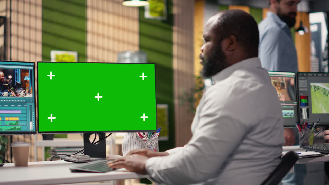 Videoeditor arbejder på computer med grøn skærm på kontor
