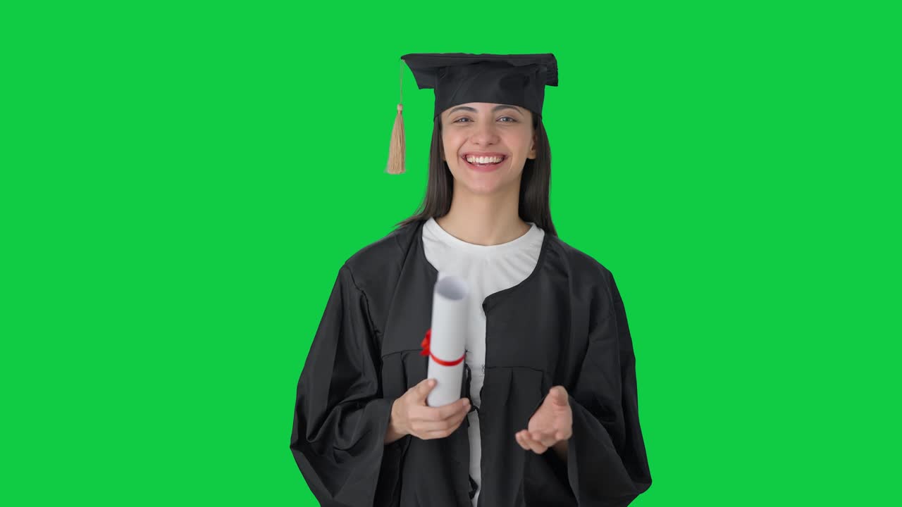 Ragazza indiana neolaureata felice che parla davanti a uno schermo verde