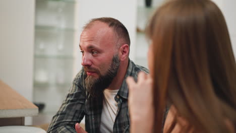 husband and wife talk sitting at table waiting for dinner