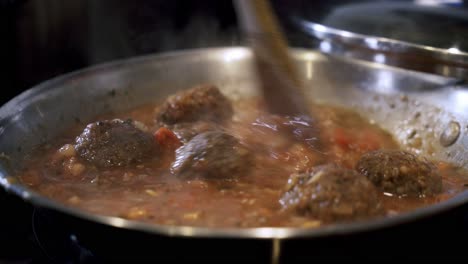salsa hirviendo de albóndigas veganas en una sartén de acero preparando ingredientes para hacer albóndiga vegana más allá con espagueti y salsa de carne