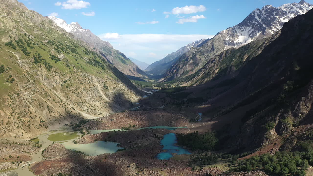 Drone shot of the mountains valley and turquoise waters at Naltar Valley in Pakistan, wide aerial shot