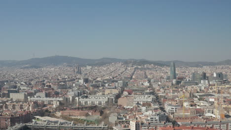 Aerial-ascending-footage-of-metropolis-on-sunny-day.-Cityscape-with-Torre-Glories-modern-design-skyscraper-and-famous-basilica-Sagrada-Familia.-Barcelona,-Spain