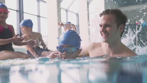 Entrenador-De-Natación-Masculino-Dando-Niño-Sosteniendo-Lección-De-Flotación-En-La-Piscina