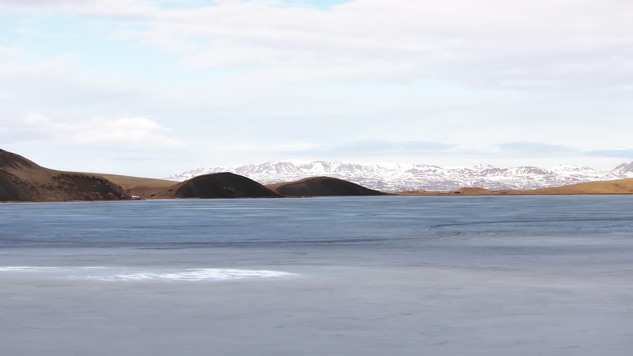 Frozen lake with volcanic hills and snowy peaks near Mývatn, Reykjahlíð, Iceland