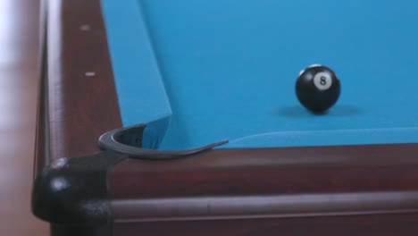 man missing final 8 ball shot in corner pocket on blue billiards table