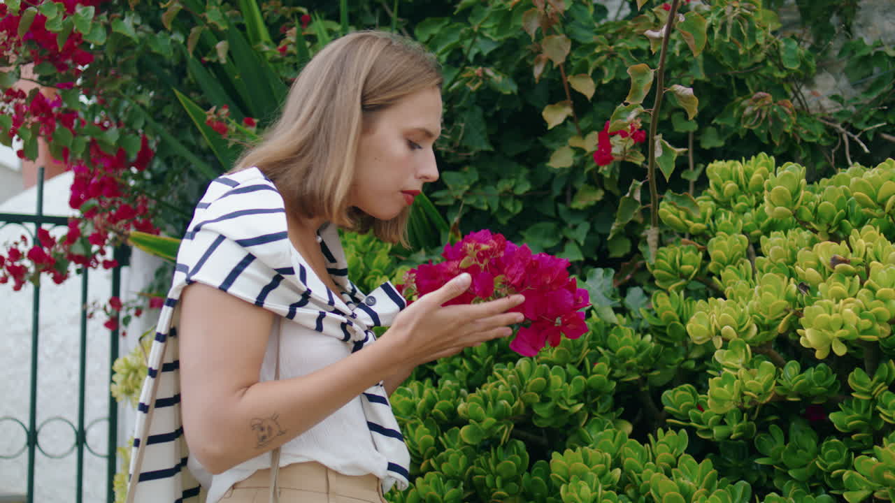 mujer oler flores de jardín en la primavera vertical. niña bonita admirar la flor rosada