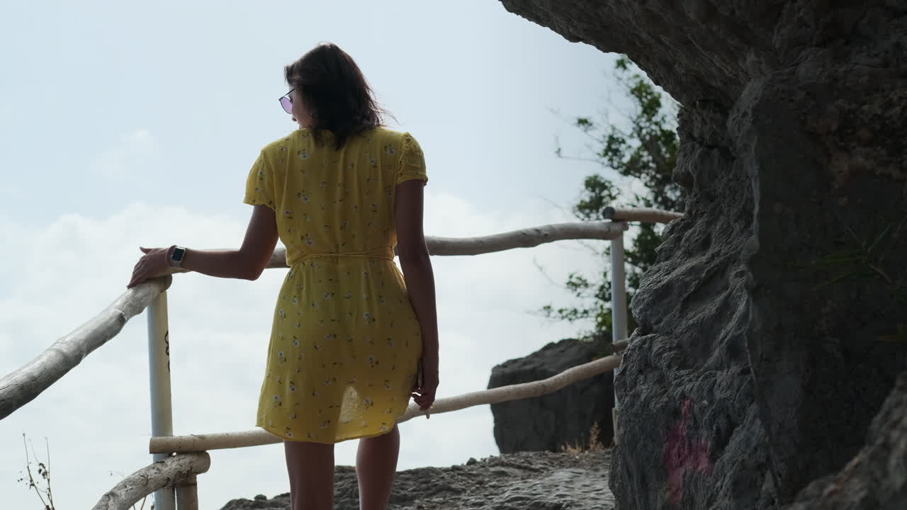 노란 드레스 를 입은 여자 가 산 을 등반 하고 있다