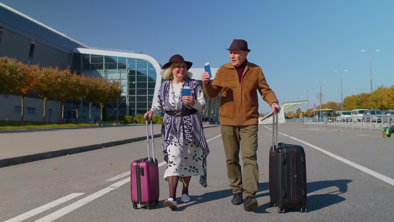 elegante pareja familiar jubilada abuela abuelo caminando con maletas de equipaje a la sala del aeropuerto