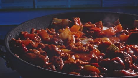 pollo picante y frijoles cocinando y chisporroteando en una sartén