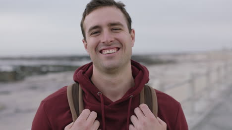 portrait-of-handsome-young-man-laughing-happy-wearing-hoodie-on-beach