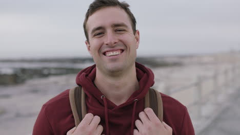 portrait of handsome young man laughing happy wearing hoodie on beach