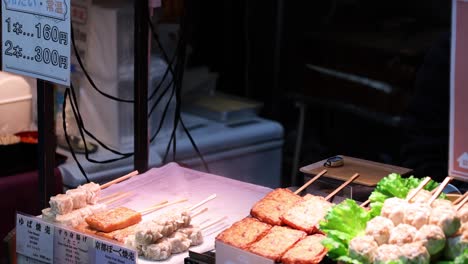 vendor preparing and selling skewered food at stall