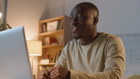 african american businessman video calling on laptop at night